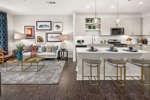 A modern kitchen and living room with a coffee table and bar stools.